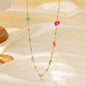 Colorful beaded flower choker necklace with gold chain on silk fabric background