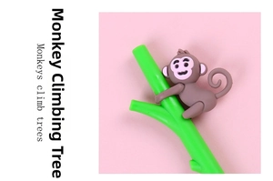 Close-up of a cute brown silicone monkey climbing a green branch on a creative gel pen