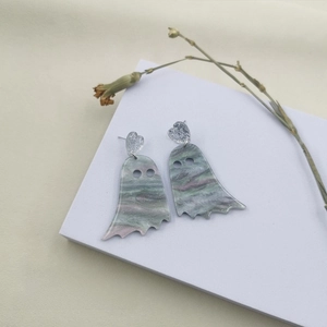Macro shot of Halloween ghost earrings with marbled acrylic texture and glittery silver hearts