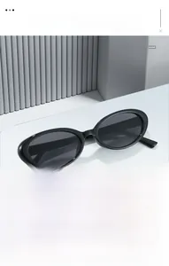 Detailed view of black oval sunglasses on a minimalist grey architectural display stand
