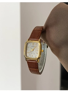 Dettaglio ravvicinato di un orologio quadrato vintage dorato con cinturino marrone