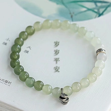 Macro detail of natural Hetian jade bead bracelet with silver coin charm on book