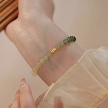 Detailed shot of gradient green jade beads with an engraved golden metal emblem