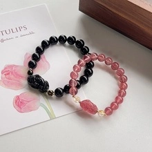 Detail of pink crystal and black stone Pi Xiu bracelets on a minimalist wooden display