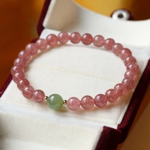 Detailed close-up of strawberry quartz beaded bracelet with a green jade accent in a gift box