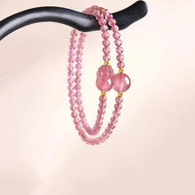 Detail of pink crystal double-layered beaded bracelet with a carved mythical beast charm