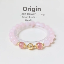 Close-up of pink quartz beaded bracelet with gold hollow bead and red crystal accents