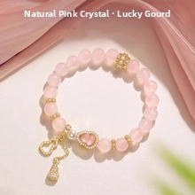 Detailed shot of a natural pink quartz bracelet with a gold gourd charm on pink silk fabric