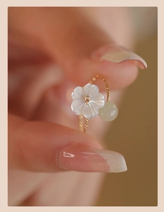 Detailed macro view of gold beaded ring featuring white petal flower and pale green jade stone