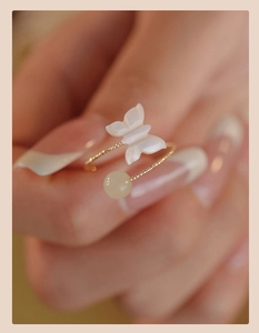 Detail of adjustable gold twisted ring featuring shell butterfly and yellow jade bead