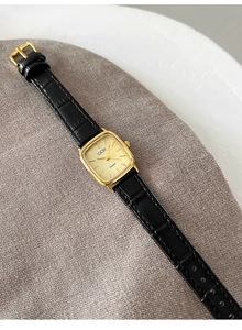 Dettaglio dell'orologio al quarzo vintage con cinturino in pelle nera e cassa dorata