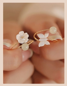 Detail of gold twisted rings with white shell flower and butterfly charms for women