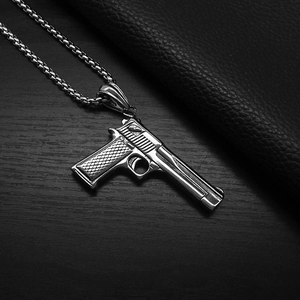Detail of a stainless steel pistol pendant with intricate grip and slide textures