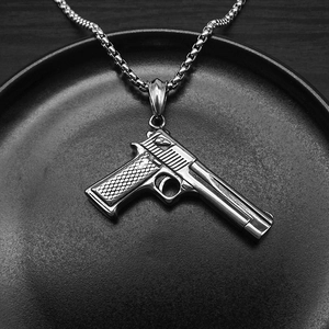 Macro shot of silver pistol pendant necklace with detailed barrel and box chain
