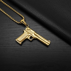 Detailed close-up of a gold pistol pendant with textured handle on dark wood