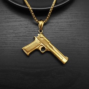 Detailed view of a gold large pistol pendant necklace with textured grip on wood surface