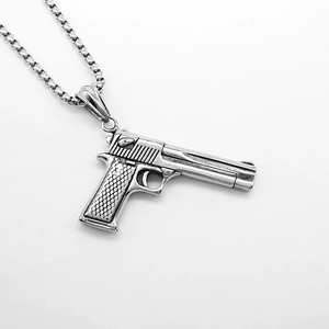 Macro shot of silver pistol pendant necklace with detailed grip texture and steel chain