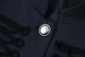 Detail of silver metallic button and black braided cord on navy blue military coat