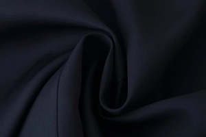 Close-up of premium dark woven fabric texture with fringe detail and elegant drape