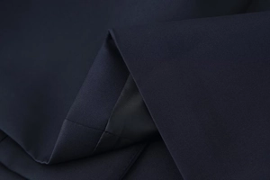 Close-up of premium dark blue fabric texture and precise stitching on suit jacket