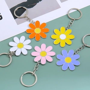 Detailed close-up of five colorful enamel daisy keychains in a flat lay arrangement