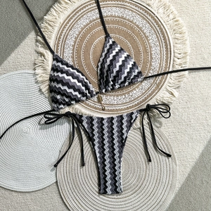 Two-piece halter bikini with monochrome chevron pattern and gold hardware on woven mats