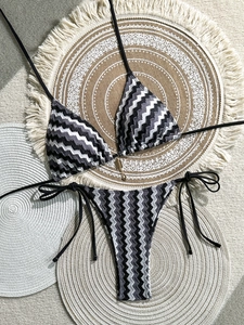 Detail of chevron knit bikini set with golden heart pendant on woven background