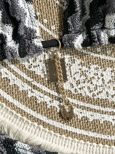 Detail of gold heart pendant and square charm on striped knit bikini fabric