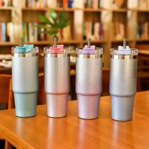 Glitter gradient 20oz stainless steel tumblers with straws on a wooden desk