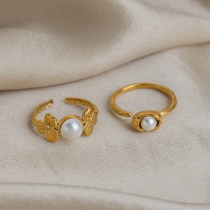 Elegant 18K gold plated stainless steel flower rings with white pearls on silk background