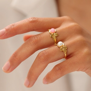 Detailed view of floral 18K gold plated rings with pink stone and white pearl insets