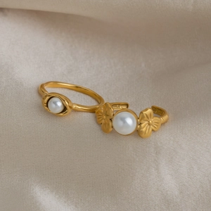 Close-up of 18K gold plated rings with white pearls and flower detail on silk fabric