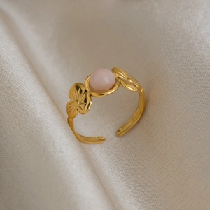 Detail of 18K gold floral ring with pink pearl on elegant white silk fabric