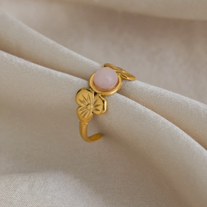 Detail of 18K gold plated flower ring featuring a round pink natural stone on fabric