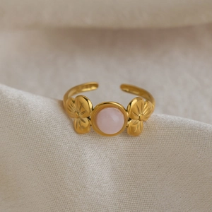 Macro view of 18K gold floral ring with round pink gemstone on silk background