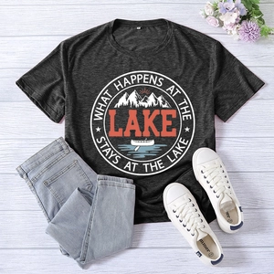 Flat lay of lake-themed graphic t-shirt with mountains and canoe on white wood background