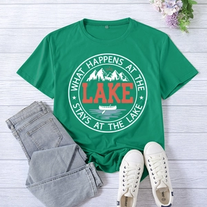 Detailed view of lake-themed graphic print on green cotton t-shirt with wood background