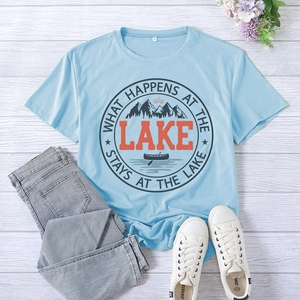 Flat lay of light blue T-shirt with lake print, jeans, and canvas shoes on wood background