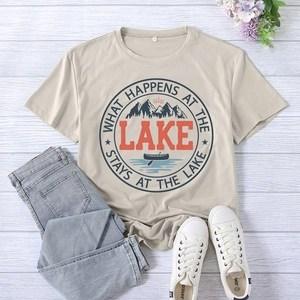Flat lay of a beige lake-themed T-shirt with vintage print on light wood background