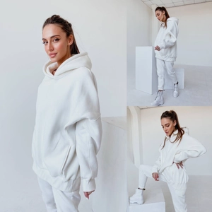 Detailansicht eines weißen Oversize-Hoodies und Jogginghosen auf weißen Requisiten