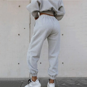 Detail view of high waist gray joggers with elastic cuffs and side pockets on a model