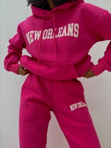 Detail eines Fleece-Trainingsanzugs in Magenta mit weißem New Orleans-Schriftzug auf Set