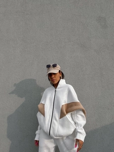 Dettaglio della giacca sportiva oversize bianca con maniche kaki e cerniera nera frontale
