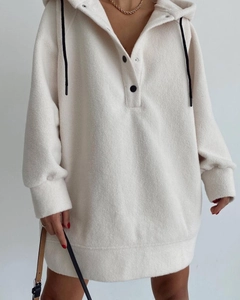 Macro shot of cream fleece texture and black button detail on oversized hoodie