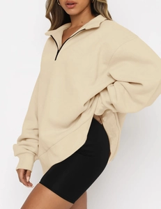 Detail view of oversized beige half-zip sweatshirt with black zipper and drop shoulder