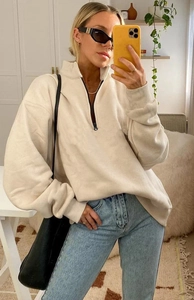 Detail of a casual half-zip sweatshirt in beige featuring drop shoulder and black zipper