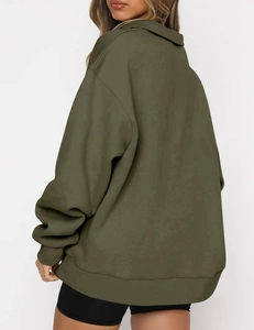 Detail of oversized dark olive green hoodie featuring dropped shoulders and ribbed cuffs