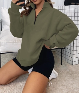 Detail of army green half-zip sweatshirt with loose fit and black collar placket detail
