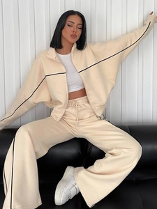 Detail eines beigen Lounge-Sets mit schwarzen Streifen an Strickjacke und Hose