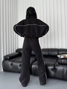 Detail eines schwarzen Trainingsanzugs mit weißen Seitenstreifen und weiter Hose